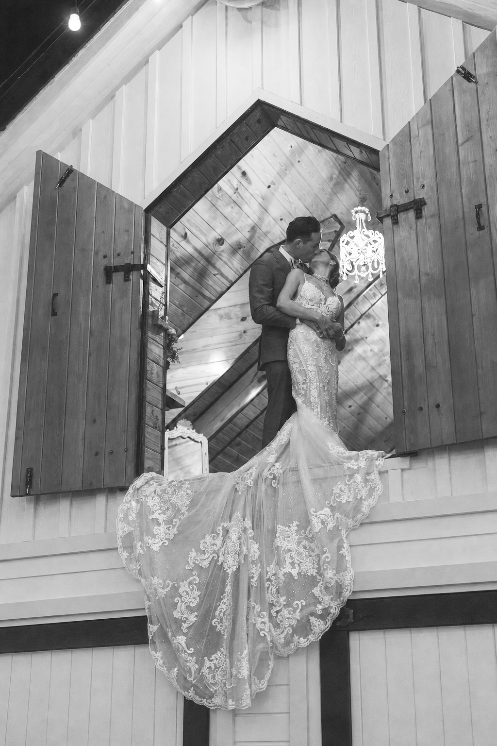 Newlyweds sharing a kiss in an open upper doorway at The Arbor Estate