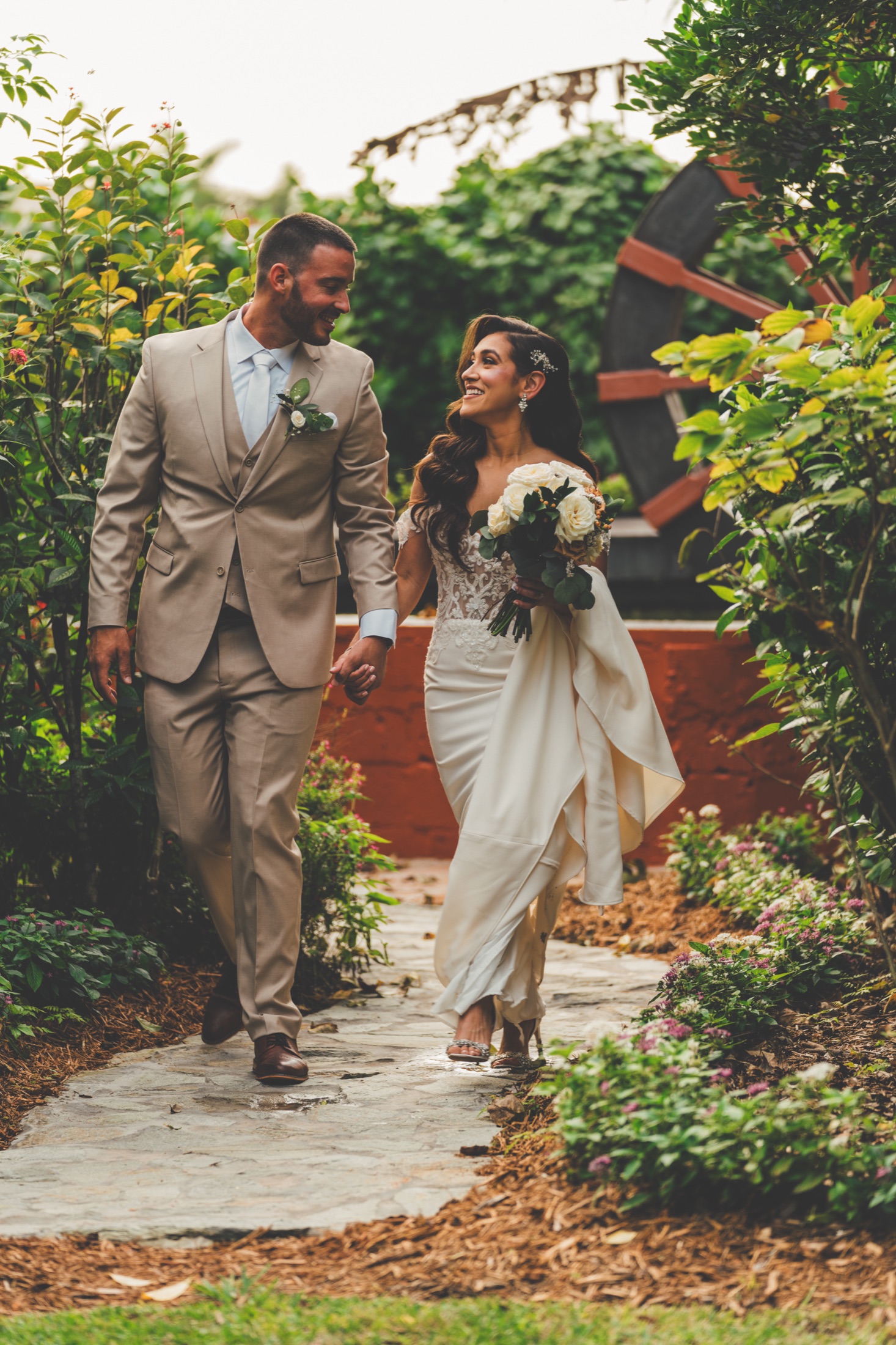 Newlyweds walking hand in hand through the tropical gardens at The Arbor Estate