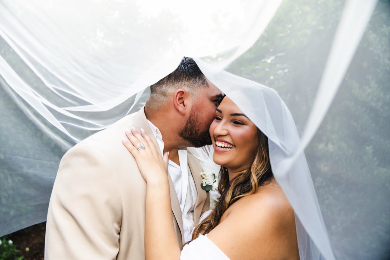 Vincent kissing Kaila’s cheek beneath her veil as she smiles