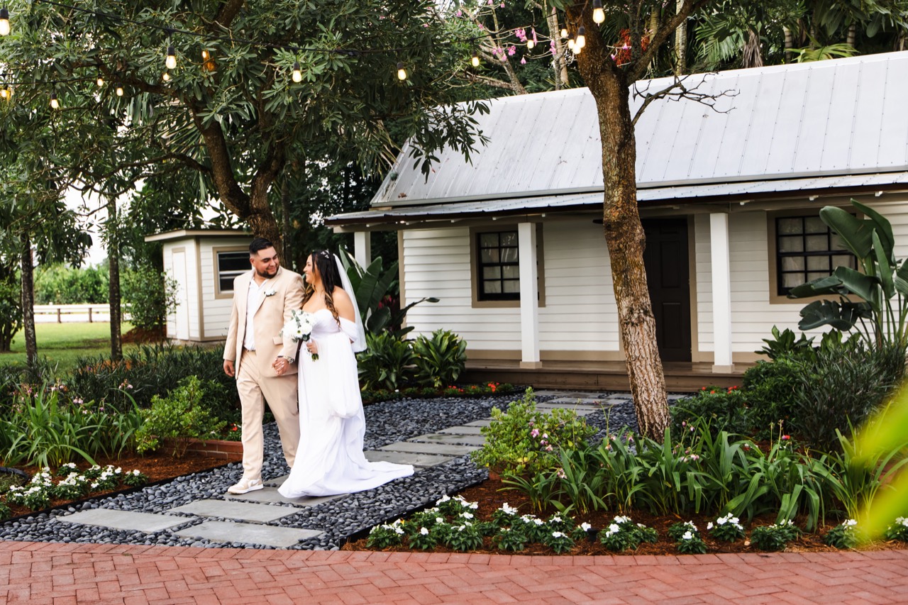 Kaila and Vincent walking hand in hand along the cottage garden path