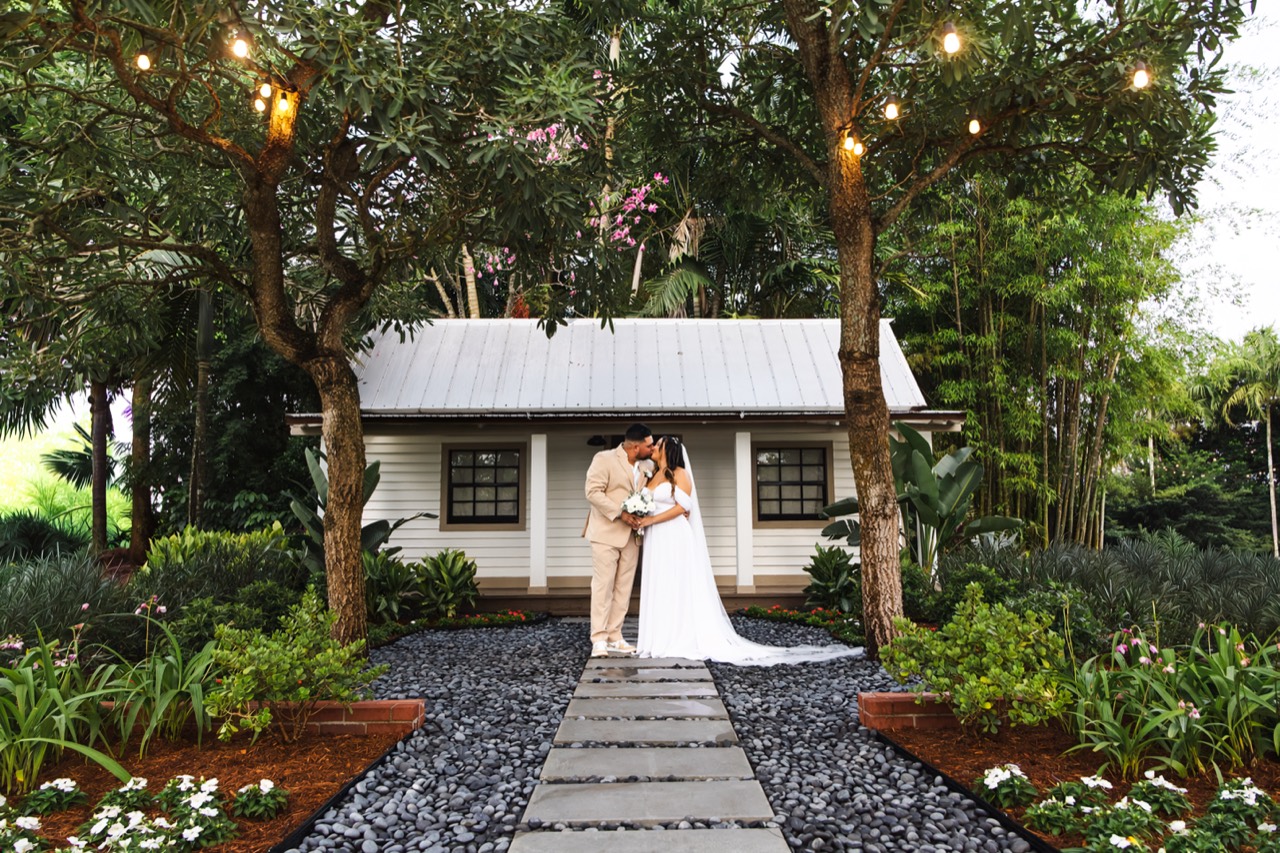 Kaila and Vincent kissing outside the cottage, framed by trees and glowing string lights