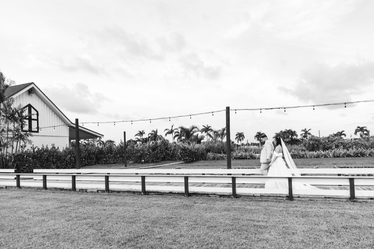 Black-and-white photograph of Kaila and Vincent walking through the estate beneath string lights