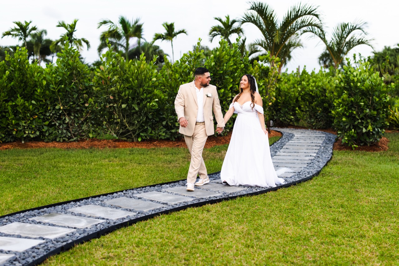 Kaila and Vincent strolling along the curved stone path surrounded by palms