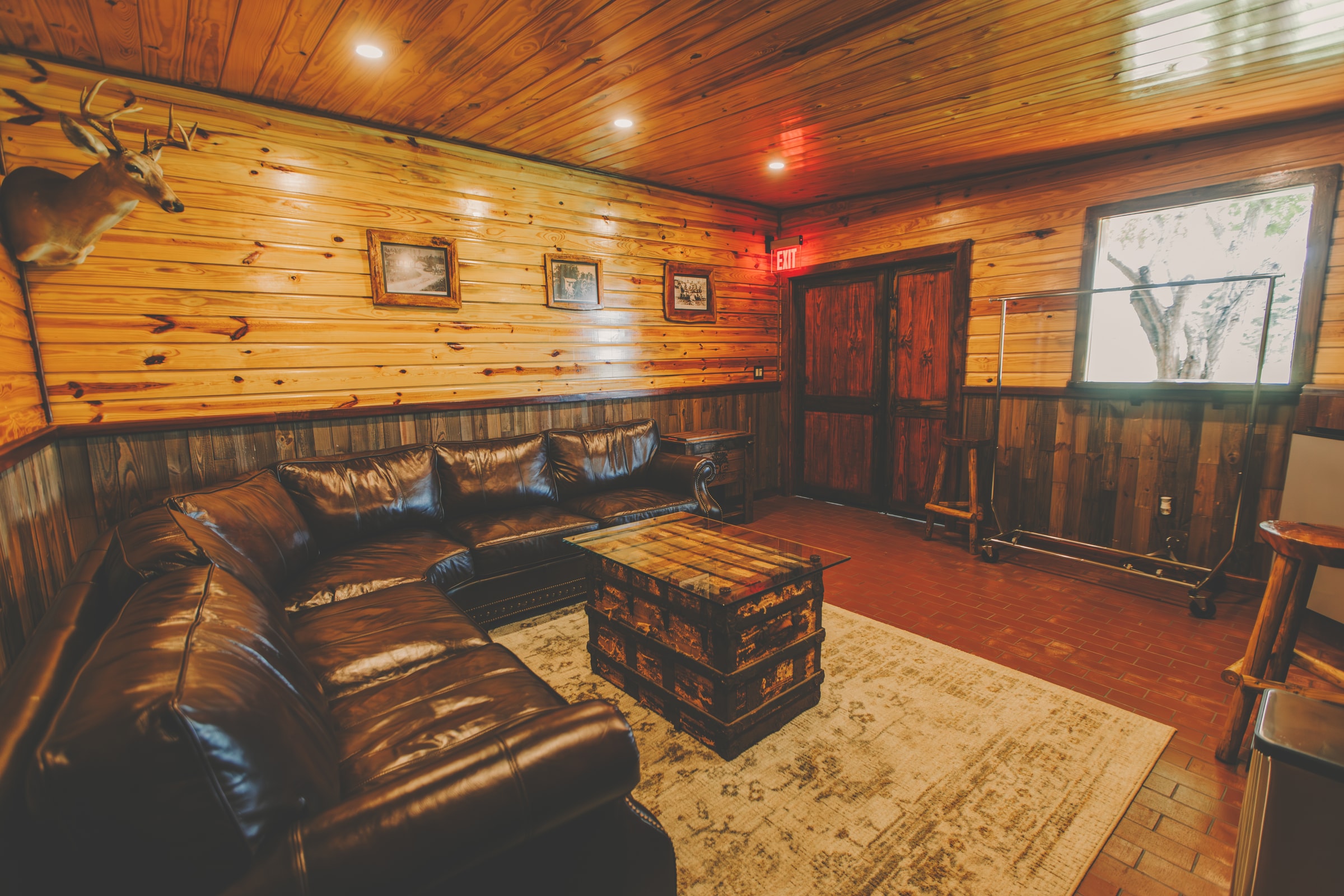 The private groom lounge at The Arbor Estate with wood-paneled walls, leather seating, and a vintage trunk coffee table